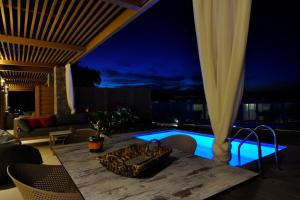 a dining table with chairs next to a pool at night at Casa del Mar in Mpoukaris