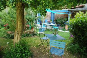 uma mesa azul e cadeiras num quintal com uma árvore em les 2 studios indépendants du clos de l'Ange em Rieux
