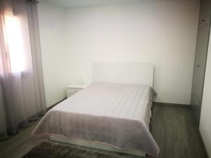 una piccola camera con un letto bianco e una finestra di Casa do Forno do Ti Correia a Macedo de Cavaleiros