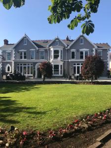 a large house with a lawn in front of it at LLwyn Country House in Llanelli