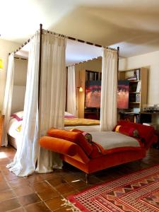 a bedroom with a canopy bed with an orange couch at La Maison d'Alice in Vézac