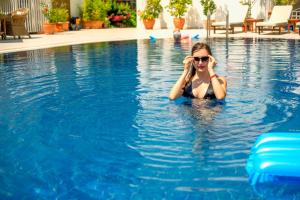 a woman in a swimming pool talking on a cell phone at S3 Hotels Orange in Oludeniz