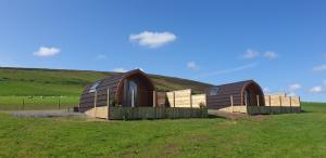 two domed buildings in a field with a hill at Lilly's Lodges Orkney Butterfly Lodge in Finstown