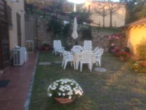 a group of white chairs and a table in a yard at Poderino Bellavista in Castellina Marittima