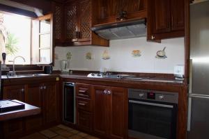 eine Küche mit Holzschränken, Spüle und Herd in der Unterkunft Luxury Villa del Mar - Bahia Feliz in Maspalomas