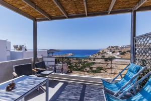 a balcony with blue chairs and a view of the ocean at Paralos Lodging in Schinoussa