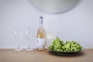 a bottle of wine and a bowl of grapes on a table at Paralos Lodging in Schinoussa