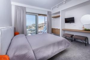 a bedroom with a bed and a desk with a television at Paralos Lodging in Schinoussa
