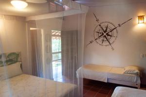 a room with two beds and a compass on the wall at Jangada Lodge in São Miguel do Gostoso