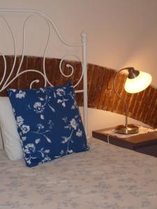 a bed with a blue pillow and a lamp at Páteo dos Oliveira - Casa dos Serviçais in Évora