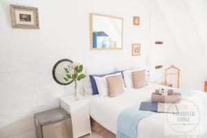 a white bedroom with a bed and a mirror at Sandriver Lodge in St Francis Bay