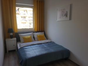 a bedroom with a bed with yellow pillows and a window at Narutowicza Modern Apartment 2 in Słupsk