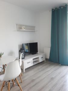 a living room with a tv and a table and chairs at Narutowicza Modern Apartment 2 in Słupsk