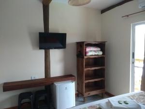 um quarto com uma cama e uma televisão num quarto em Pousada Três Marias Ilhabela em Ilhabela