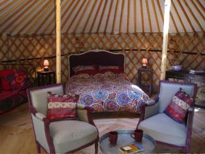 a bedroom with a bed and two chairs in a yurt at Le Mas Nomade in Callian