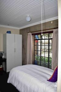 een slaapkamer met een groot wit bed en een raam bij 13 Hobson in Secunda
