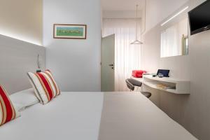 Habitación de hotel con cama blanca y escritorio en Hotel Maria Serena, en Rímini