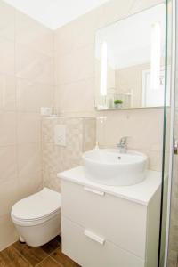 La salle de bains blanche est pourvue d'un lavabo et de toilettes. dans l'établissement Apartman M&D, à Split