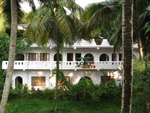 un edificio blanco con palmeras delante en Jickys Nest, en Varkala