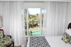 - une chambre avec un lit et une grande fenêtre dans l'établissement Coco Palm, à Gros Islet
