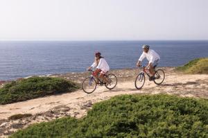 two people riding bikes on a dirt road near the ocean at Sagres Time Apartamentos in Sagres