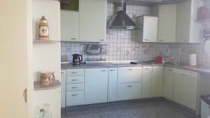 a white kitchen with white cabinets and a sink at Dom Gościnny Wisteria in Andrychów