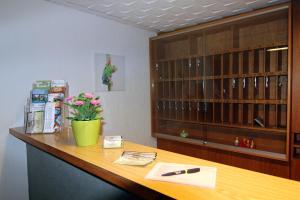 een bureau in een kantoor met een vaas met bloemen erop bij Hotel Sunny Side Up in Dauchingen