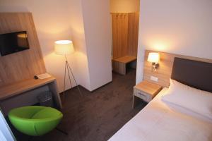a bedroom with a bed and a green chair at Hotel Sunny Side Up in Dauchingen
