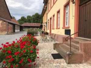 a courtyard of a building with red flowers at Elegantes Gästeapartment Verano in Schloß und Hofgut Langenzell in Wiesenbach