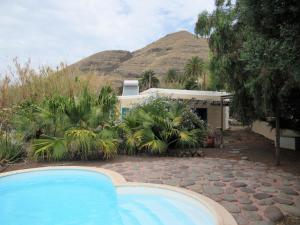 a swimming pool in front of a house with a mountain at vivelorural Casa en risco de agaete con piscina in Agaete