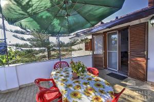 a table and chairs with a green umbrella on a patio at Casavacanzeinsicilia Etna Taormina in Piedimonte Etneo
