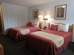 Cette chambre d'hôtel comprend 2 lits avec des draps rouges et blancs. dans l'établissement Red Carpet Motel - Knoxville, à Knoxville