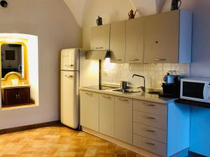 a kitchen with white cabinets and a white refrigerator at San Michele delle grotte BnB in Gravina in Puglia