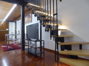 a living room with a tv and a staircase at Giudei House Suite Bologna in Bologna