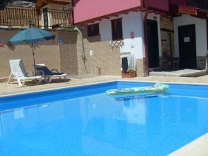 ein großer blauer Pool mit Sonnenschirm und Stühlen in der Unterkunft The Pink House in Polkownik Serafinowo