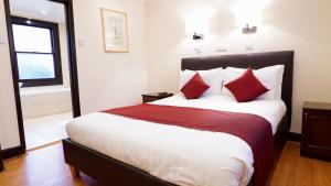 a bedroom with a large bed with red pillows at La Gaffe - Bed and Breakfast in London