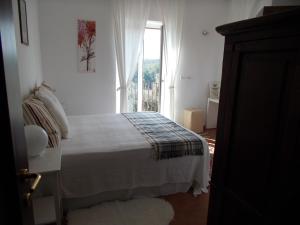 a white bedroom with a bed and a window at La Masseriola agriturismo in Caianello Vecchio