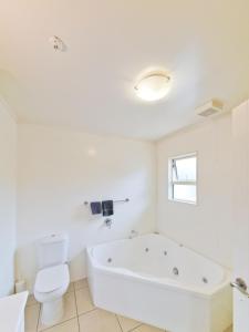 baño blanco con bañera y aseo en ASURE Avenue Motor Lodge, en Timaru