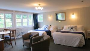 um quarto de hotel com duas camas e uma mesa e cadeiras em Cheltenham House em Hanmer Springs