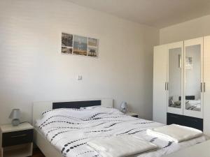 ein weißes Schlafzimmer mit einem Bett und einem Spiegel in der Unterkunft Apartmani Dujmovic in Kaštela