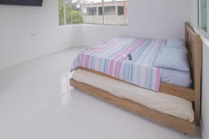 1 cama con marco de madera en una habitación blanca en Habitacion Coveñitas 2A, en Coveñas