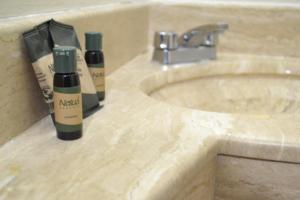 a bathroom sink with two bottles of moisturizers on it at Hotel America Centro in Los Mochis