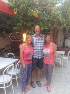 un hombre y dos mujeres parados frente a un naranjo en Pension Casa Austria en Calella
