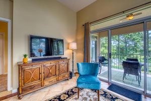 sala de estar con TV y silla azul en Cypress Point Condominiums at Craft Farms #306B en Gulf Shores