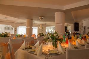 a room with white tables and chairs with flowers on them at Motelik Lord in Gorzów Wielkopolski