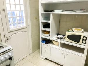 cocina con armario blanco y microondas en Cosy apartment @ La marsa Corniche-Beach en La Marsa