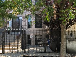 ein schwarzer Zaun vor einem Gebäude mit einem Baum in der Unterkunft Brooklyn's Finest - Cozy 2 Bedroom in Brooklyn