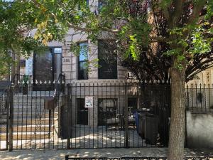 a black fence in front of a building with a tree at Brooklyn's Finest - Cozy 2 Bedroom in Brooklyn