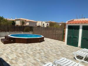 a patio with a pool and chairs and a fence at Guest House Alfarrobeiras in Albufeira