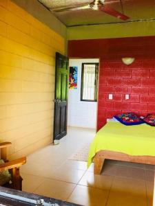 Habitación con cama y pared de ladrillo rojo. en Casa Guajira en Montezuma